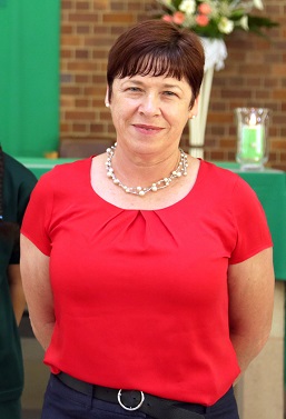 School staff member standing outdoors wearing a red top.